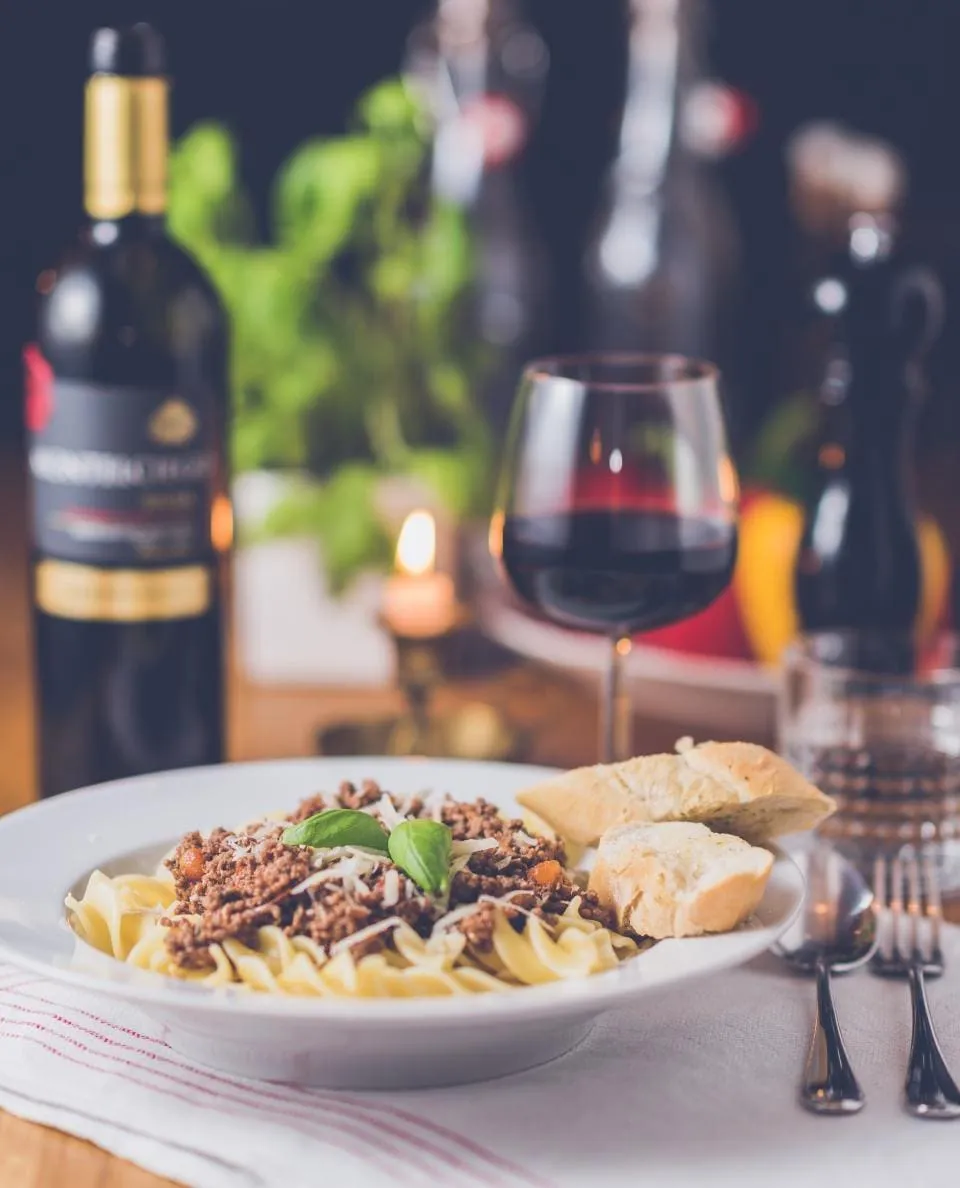 A pasta course and red wine at a candlelit restaurant table